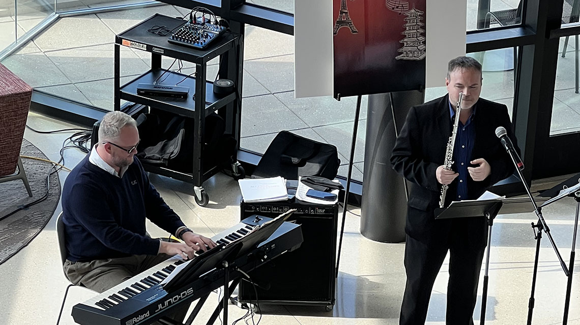 Jeremy Benson plays the flute for attendees in the atrium of Merrill Hall